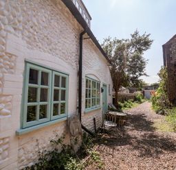 An outdoor area with a table and chairs beside a pathway at Buttercup, Blakeney, Norfolk