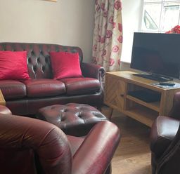 A living room with a sofa, armchair, and tv at The Bittern in Blakeney, Norfolk