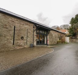 An exterior view of a stone building with windows and a cobblestone path at The Barn at Sunny Barn in Brecon