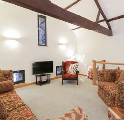 A living room with a sofa and television at The Barn at Sunny Barn in Brecon