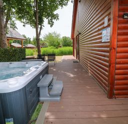 An outdoor area with a hot tub next to a wooden deck at Sunnyside Lodge Thorpe-On-The-Hill