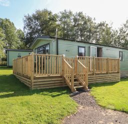 A cabin with a wooden deck and steps at Barnes Retreat in Carnforth