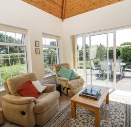 A conservatory with seating area and sliding doors leading to patio at Knockroe Lodge