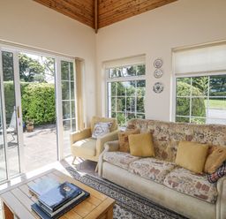 A conservatory with a sofa and armchair at Knockroe Lodge