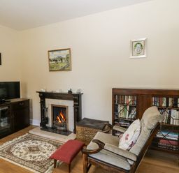 A living room with a fireplace and bookshelves at Knockroe Lodge