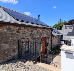 An outdoor view of a cottage with solar panels at Hedgehog Highway in Parkham