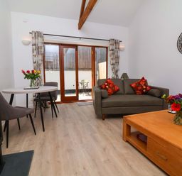 A living room with a sofa, coffee table and dining area at Hedgehog Highway Parkham
