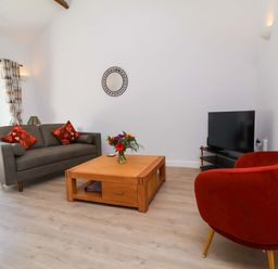 A living room with a sofa, coffee table and television at Hedgehog Highway, Parkham