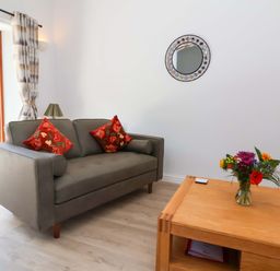 A living room with a sofa and a flower vase at Hedgehog Highway in Parkham
