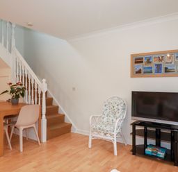 A living room with a dining table and television at Acorns in Falmouth