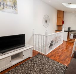 A living room with a tv and kitchen in Bobby's Whitby