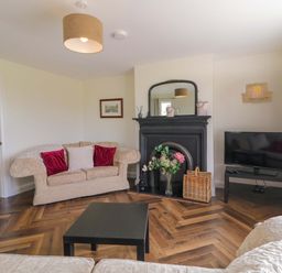 A living room with a sofa, fireplace, and television at Ard Na Mara