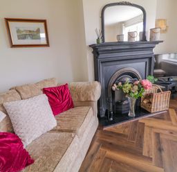 A living room with a sofa, fireplace, and television at Ard Na Mara