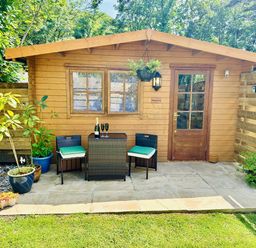 An outdoor area with a log cabin, table, and chairs at Harvey's Lodge in Lowertown, Helston