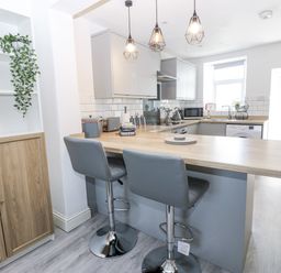 A kitchen with a countertop and bar stools at Keekle Terrace in Cleator Moor