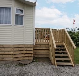 An outdoor area with a wooden deck and steps at Puffin in St Bees
