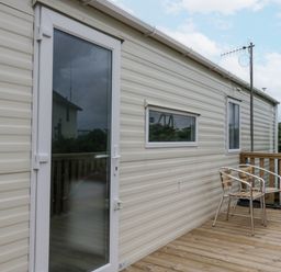 A deck with chairs and a doorway at Puffin in St Bees