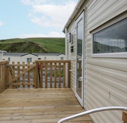 A deck area with a wooden gate and door at Puffin in St Bees