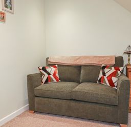 A living room with a sofa and decorative items at Mini Mena in St Austell