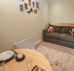 A living room with a sofa and a table set for dining at Mini Mena in St Austell