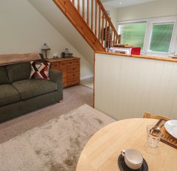 A living room with a sofa and a dining table at Mini Mena in St Austell