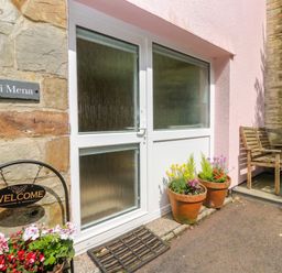 An outdoor entrance with a door and flower pots at Mini Mena in St Austell