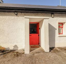 An entryway with a red door and windows at Kate's Cottage