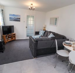A living room with a sofa and dining table at 51 Longstone Park