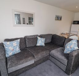 A living room with a sofa and dining area at 51 Longstone Park