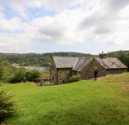 A stone house with a garden near a lake at Ty Newydd Llanrhychwyn near Llanrwst