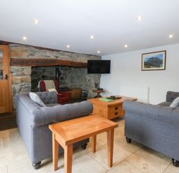 A living room with a sofa and coffee table at Ty Newydd Llanrhychwyn near Llanrwst