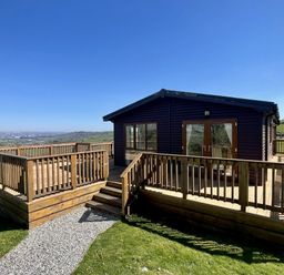 A lodge with a deck and steps at Lowena Lodge Whitsand Bay Holiday Park near Millbrook