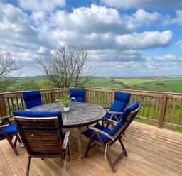 A dining area with a round table and chairs at Lowena Lodge Whitsand Bay Holiday Park near Millbrook