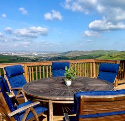 An outdoor seating area with a round table and chairs at Lowena Lodge Whitsand Bay Holiday Park near Millbrook