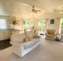 A living room with a sofa and dining area at Lowena Lodge Whitsand Bay Holiday Park near Millbrook
