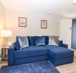 A living room with a blue sofa and lamp at Seaspray in Beadnell