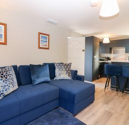 A living room with a sofa and kitchen island at Seaspray in Beadnell