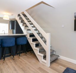 A living room with stairs and bar stools at Seaspray in Beadnell