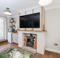A living room with a fireplace and television at Firefly Cottage