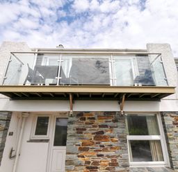 A balcony with glass railings and stone exterior at 9 Slipway Cottages Rock
