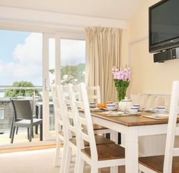 A dining room with a table and chairs at 9 Slipway Cottages in Rock