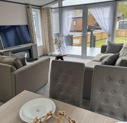A living room with a sofa, television, and table at Lime Tree Lodge