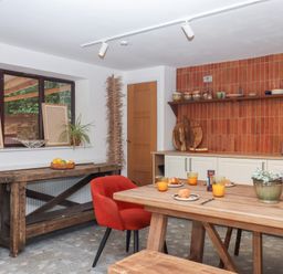 A kitchen with a wooden table and orange juice at Tigley Meadow Coach House in Totnes