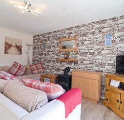 A living room with a sofa, television, and decorative wall at Boo’s Bungalow in Callington near Gunnislake