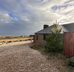 An outdoor view of a house with a gravel driveway at Cobble Stone Cottage near Leabgarrow, County Donegal