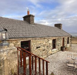A cottage with stone walls and outdoor seating at Cobble Stone Cottage near Leabgarrow, County Donegal