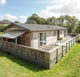 A lodge with decking and glass railing in the garden at 2 Tree Tops in Lanreath