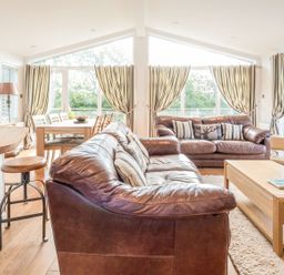 A living room with a sofa and dining area at 2 Tree Tops in Lanreath