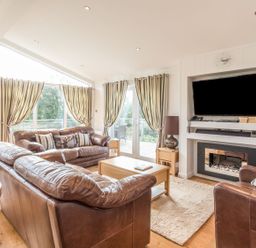 A living room with a sofa and television at 2 Tree Tops in Lanreath