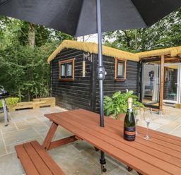 An outdoor area with a table, champagne, and cabins at Charltons Hollow Cabin in Haywards Heath